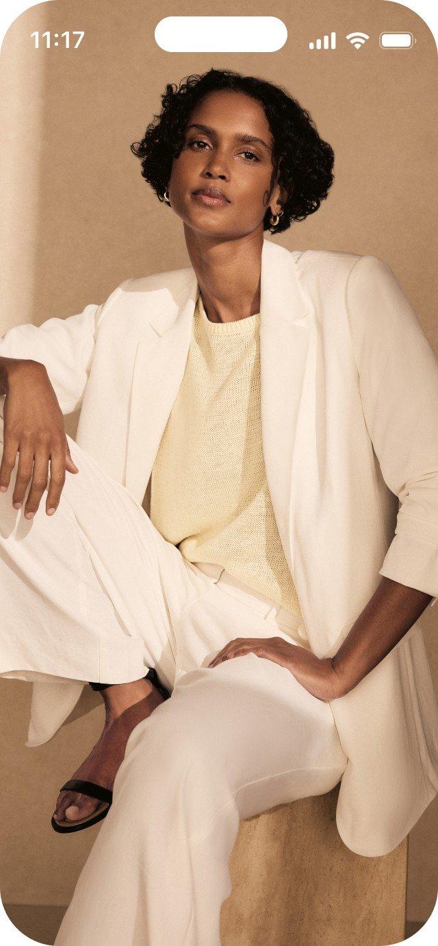a woman in a white suit sitting on a stool