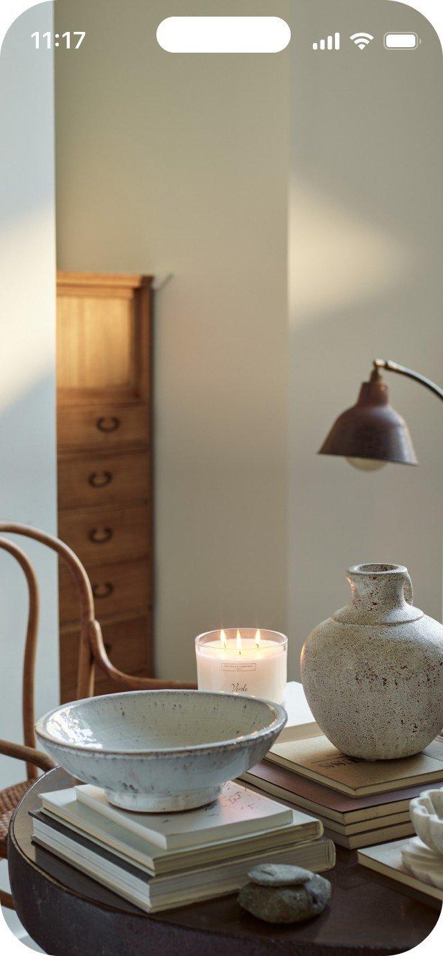 a table with a lamp, a vase, and a candle on it