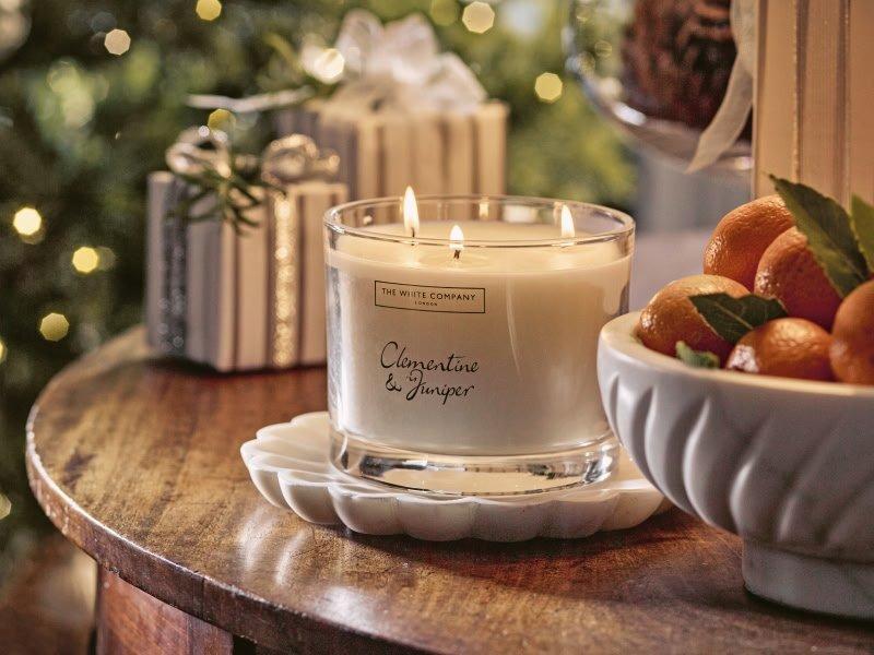 a candle is sitting on a table next to a bowl of oranges