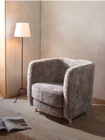 a grey chair sitting in a room with a lamp and a magazine