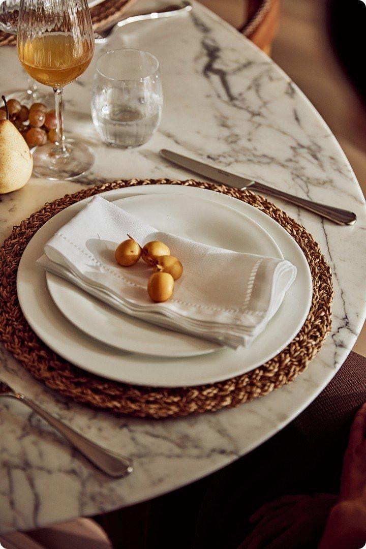 a white plate with a white napkin on it sitting on a marble table