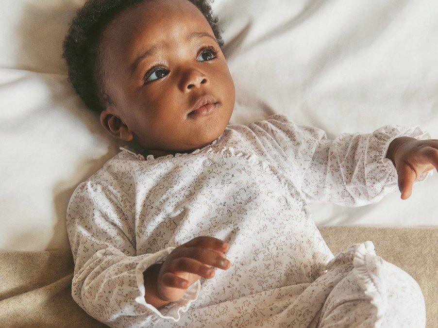 a baby laying on a bed with a white blanket