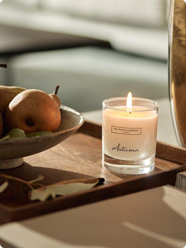 a tray with a candle and a bowl of pears