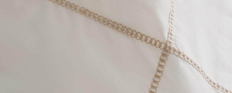 a close up of a white sheet with a gold rope