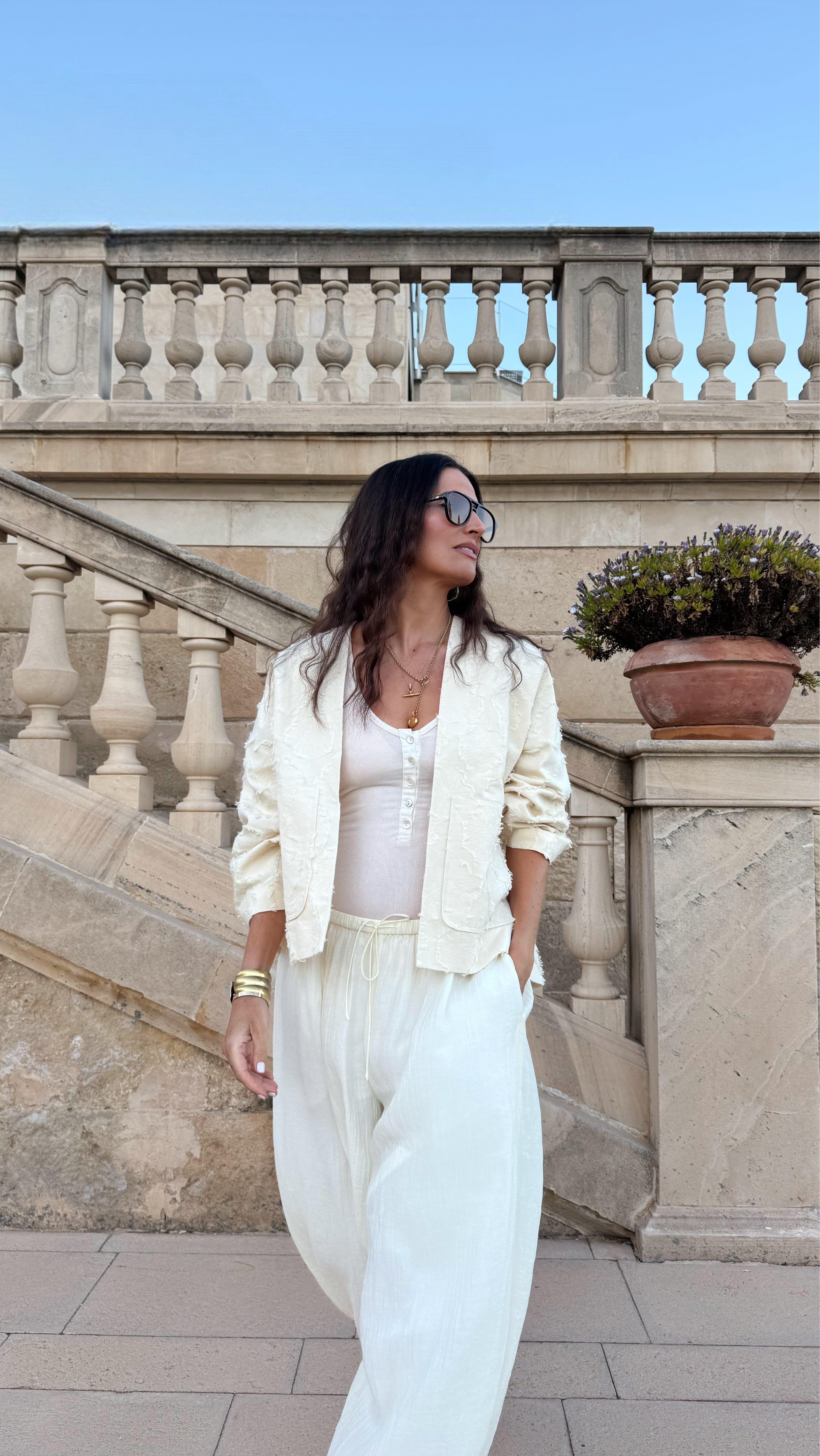a woman in white pants and jacket standing on steps