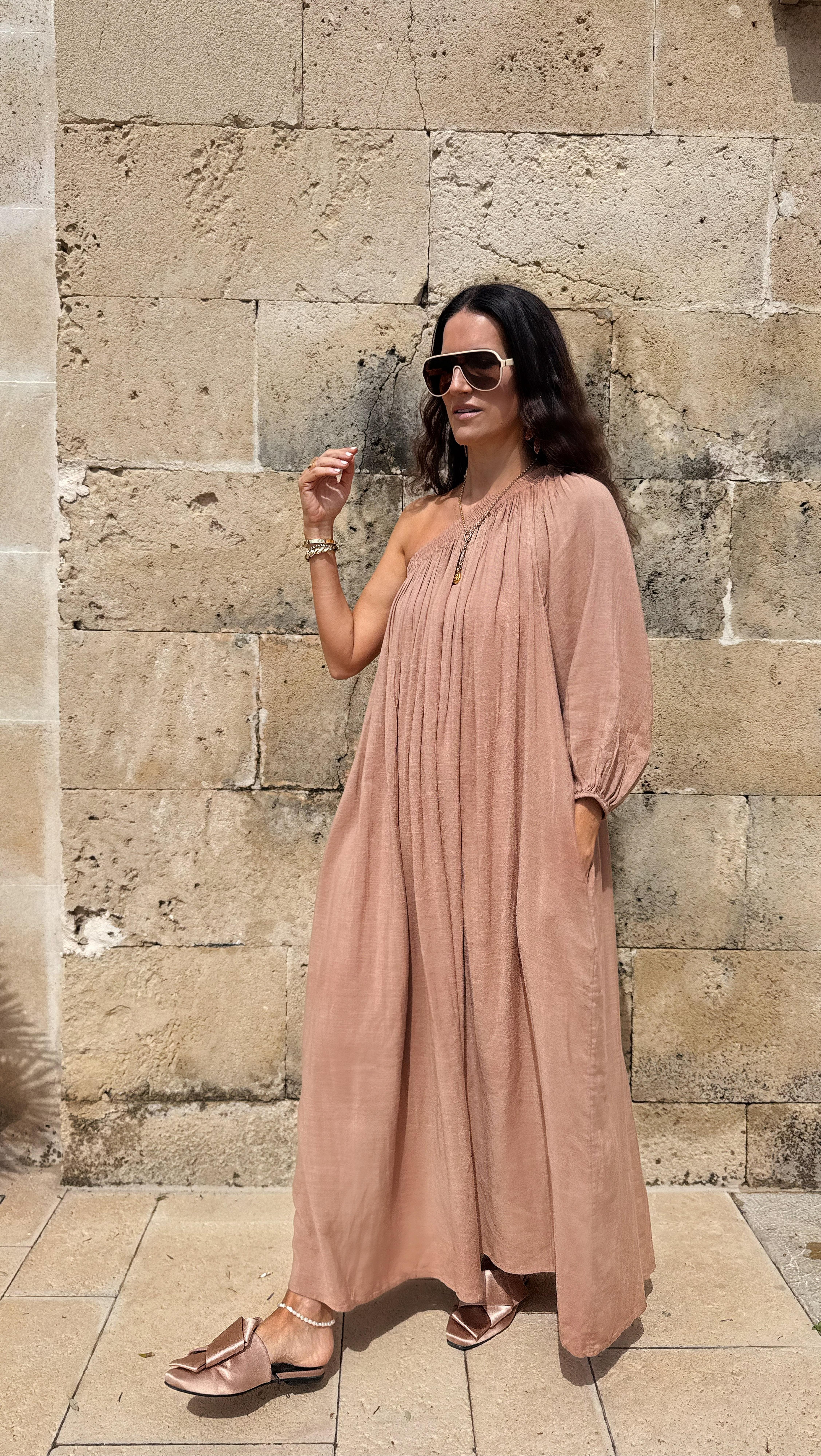 a woman in a long dress standing next to a wall