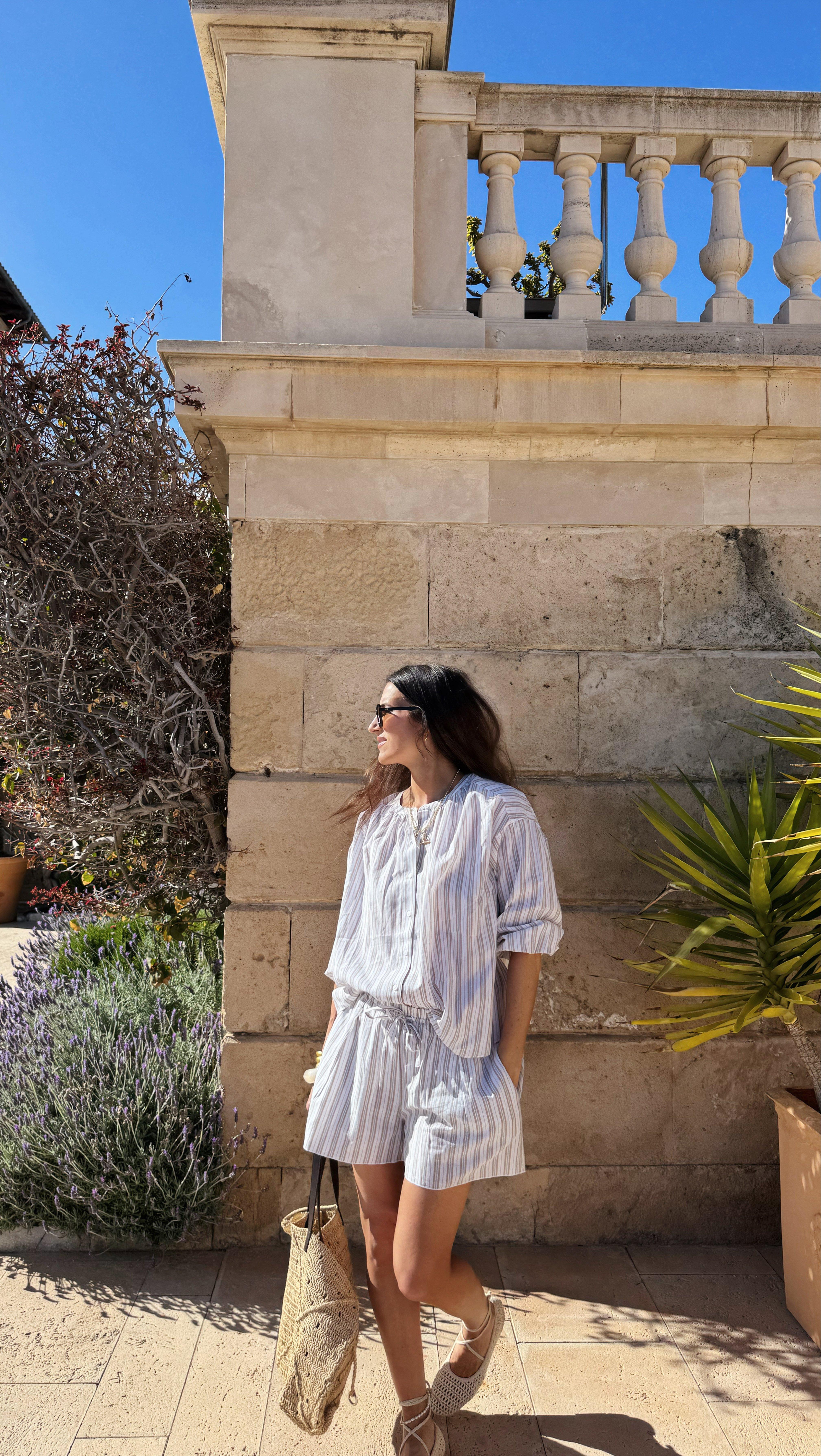 a woman in a white dress and sunglasses standing next to a wall