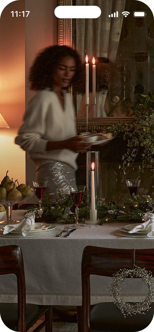 a woman standing in front of a table with candles and a plate of food