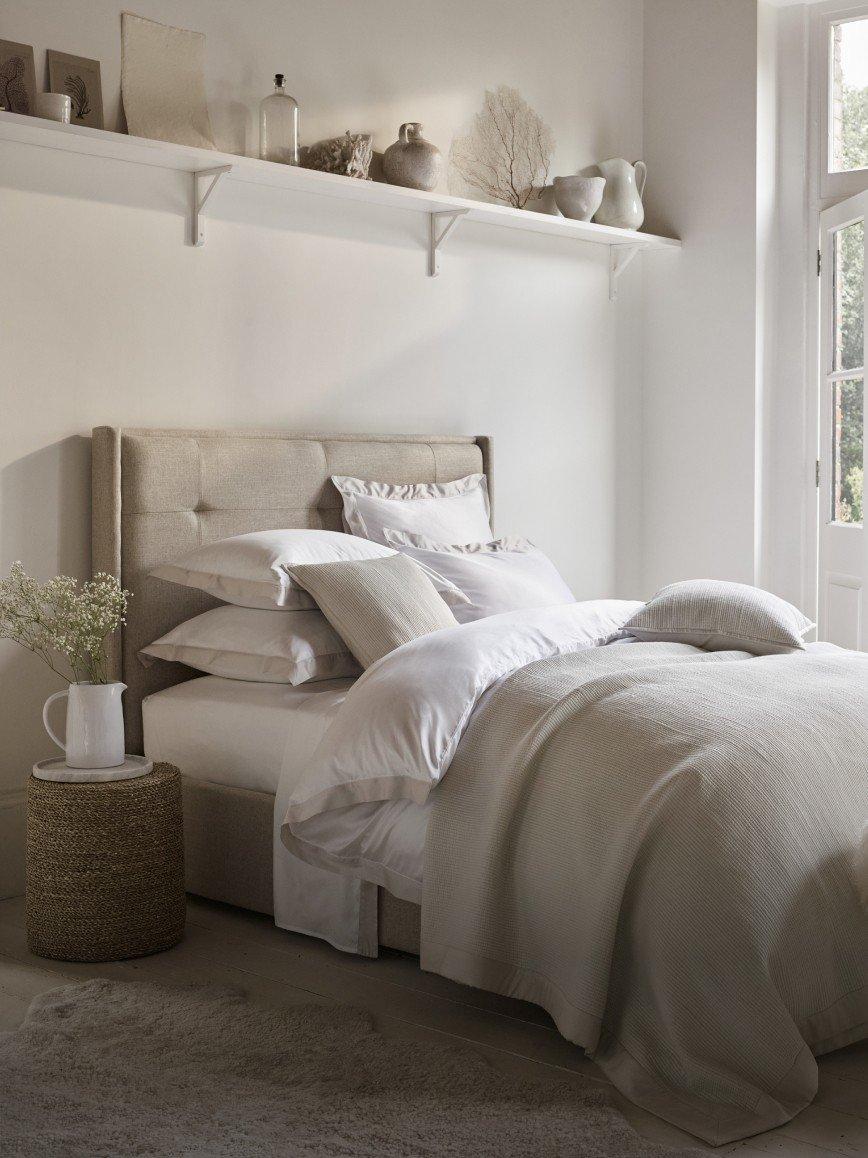 a bed with white sheets and pillows in a bedroom