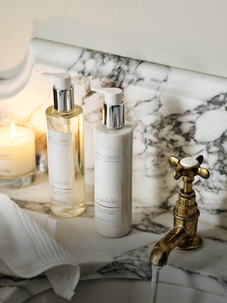 a bathroom sink with two bottles of lotion and a candle