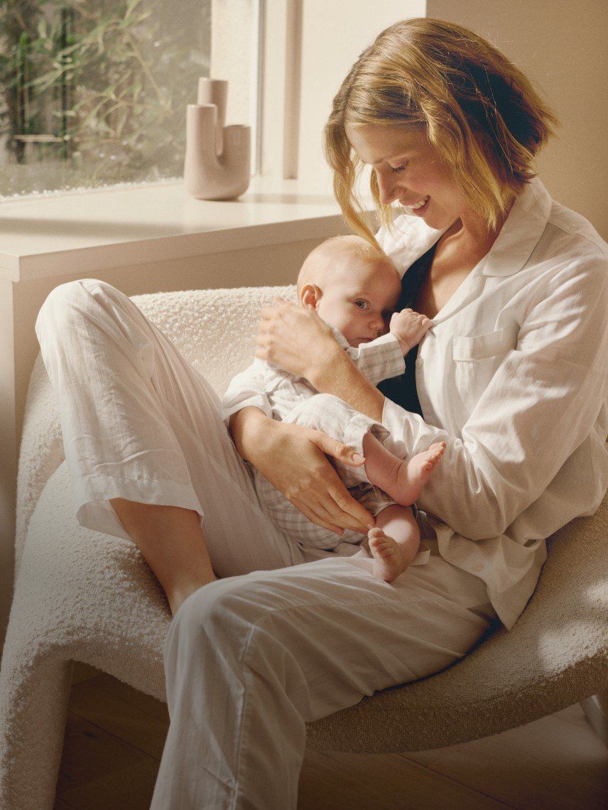 a woman holding a baby in her arms while sitting on a bed