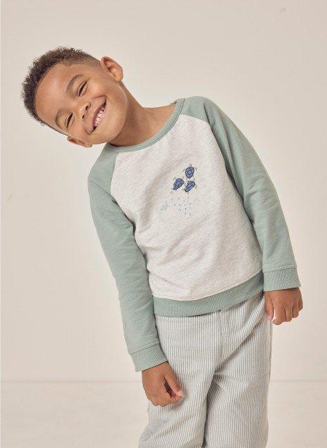 a young boy smiling while standing on a white background