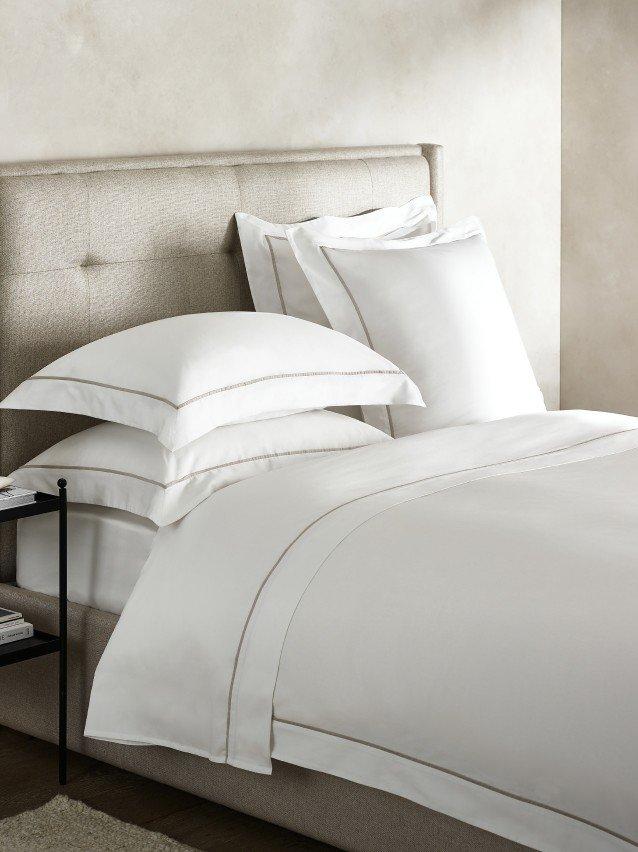 a bed with a white comforter and pillows on it