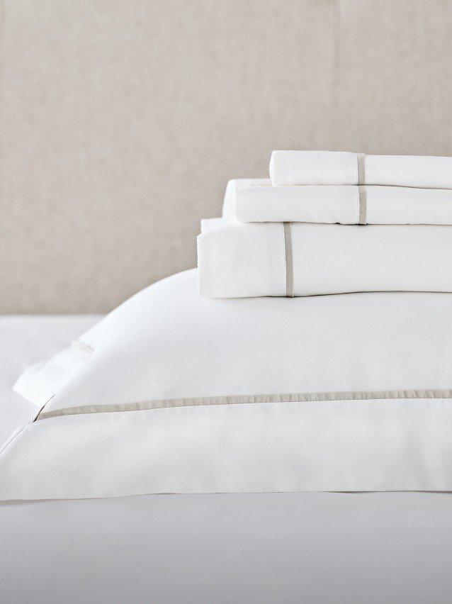 a stack of white sheets on top of a bed