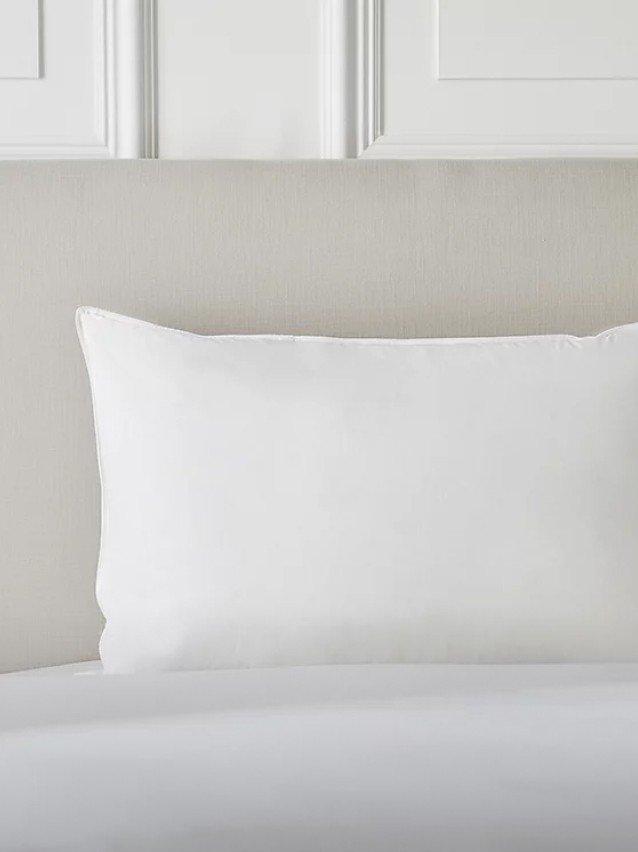 a white pillow on a bed with a white headboard