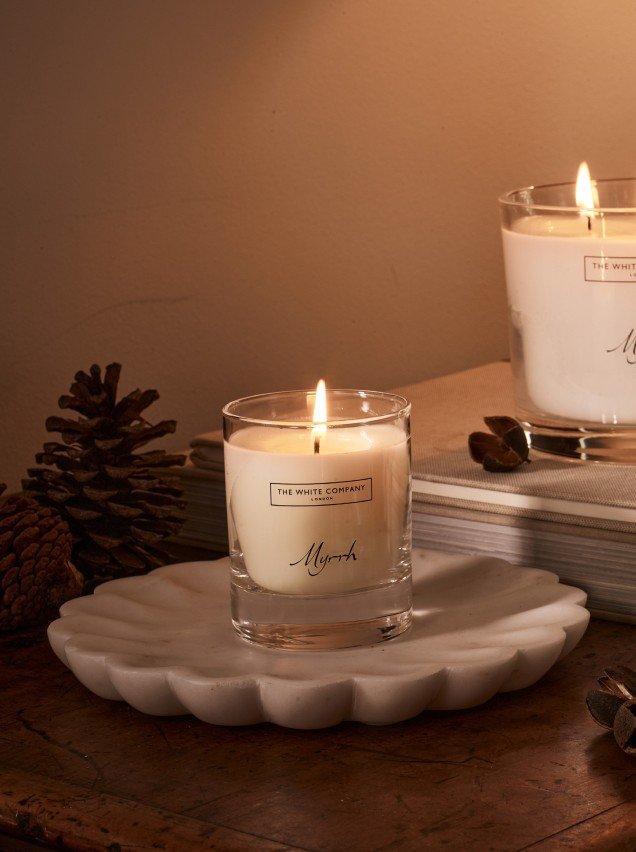 two candles on a table next to a pine cone