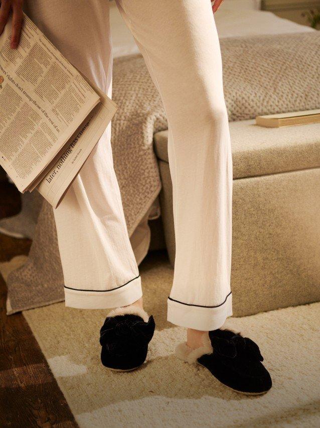 a person in pajamas holding a book and standing in a bedroom