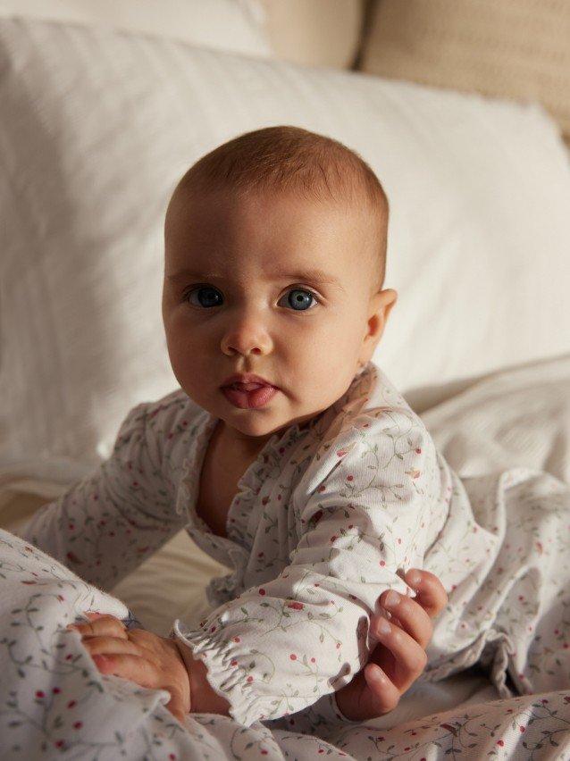 a baby laying on a bed with a parent holding it