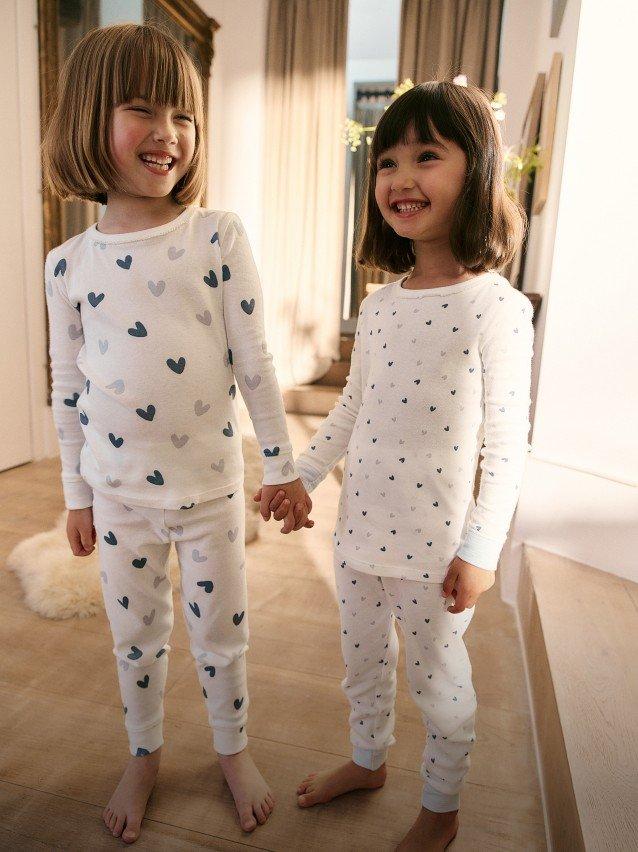 two little girls in matching pajamas holding hands in a room