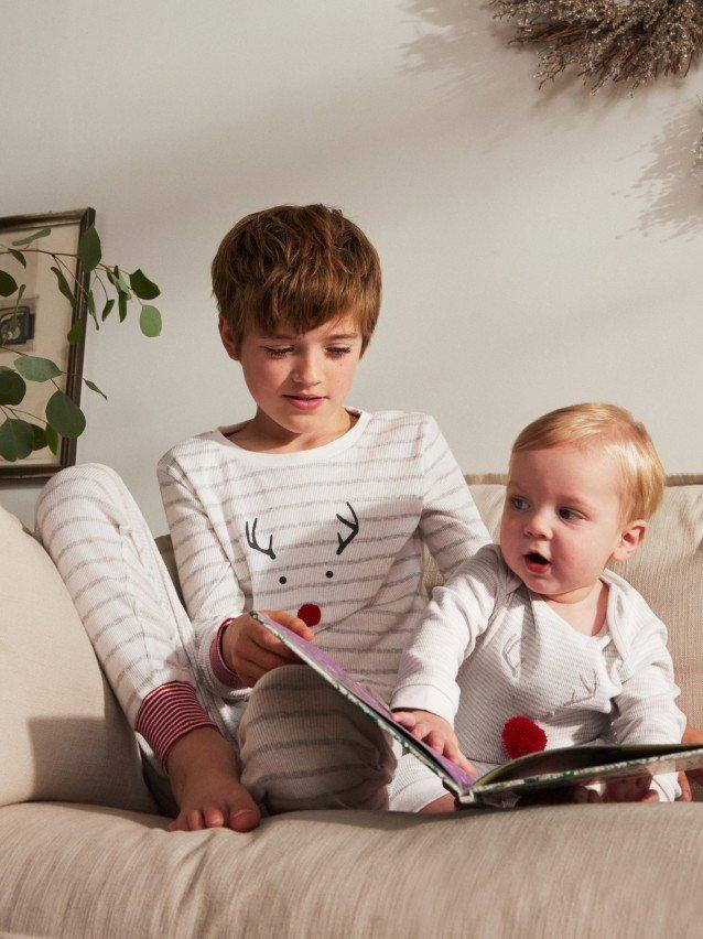 a boy and girl sitting on a couch reading a book