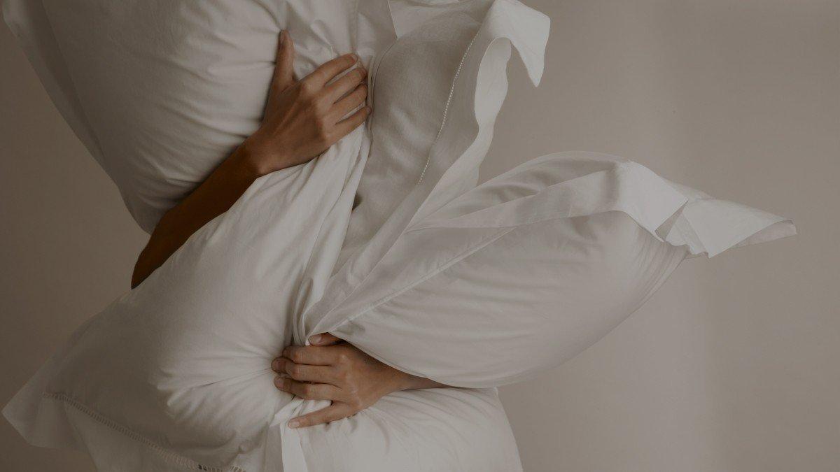 a woman is holding a pillow over her head and shoulders