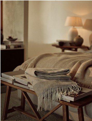 a bed with a blanket on it and a lamp on the table