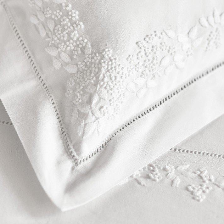 a close up of a white sheet with a white embroidered design