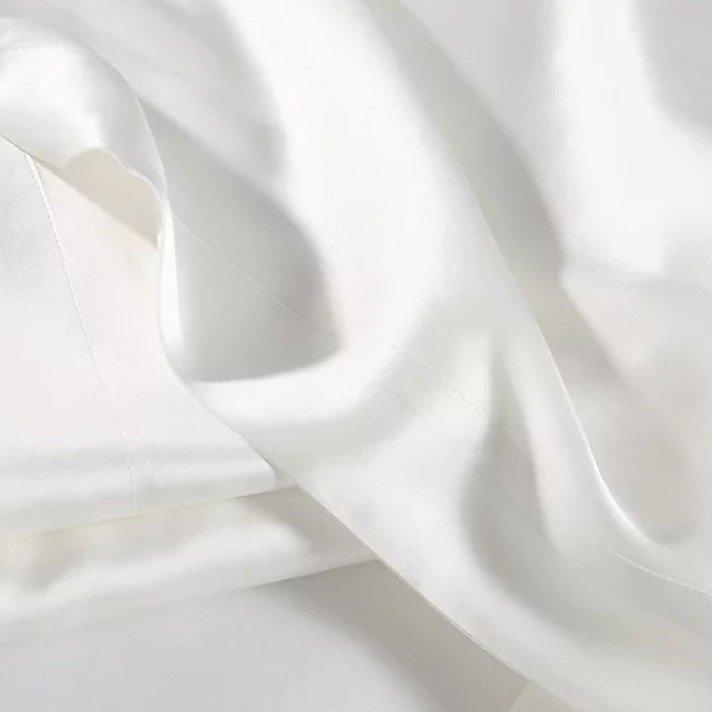 a close up of a white sheet with a white pillow