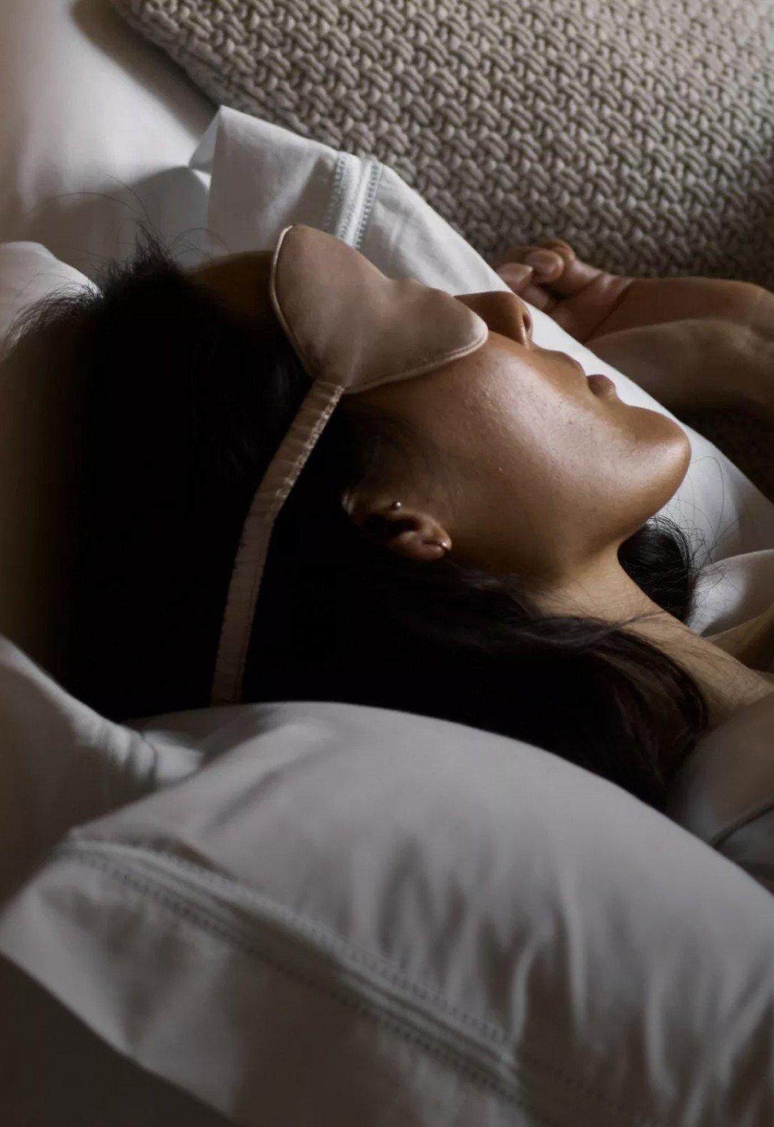 a woman sleeping with a blindfold on in bed