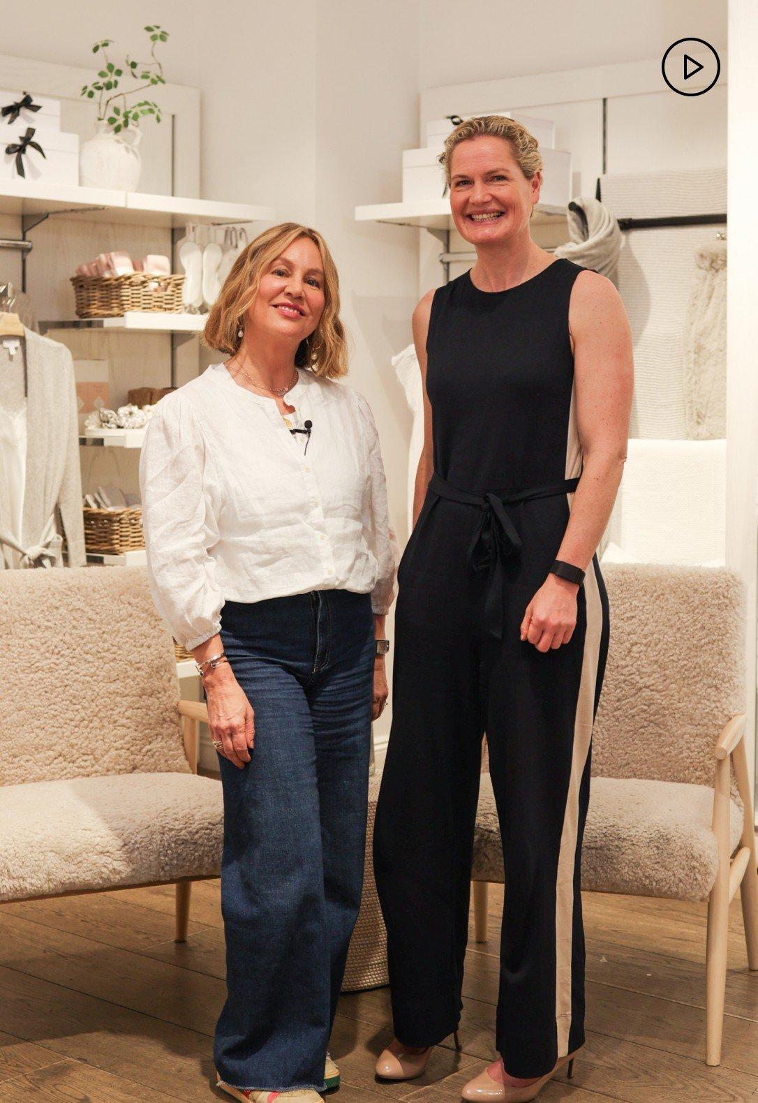 two women standing in a room with a couch and chairs