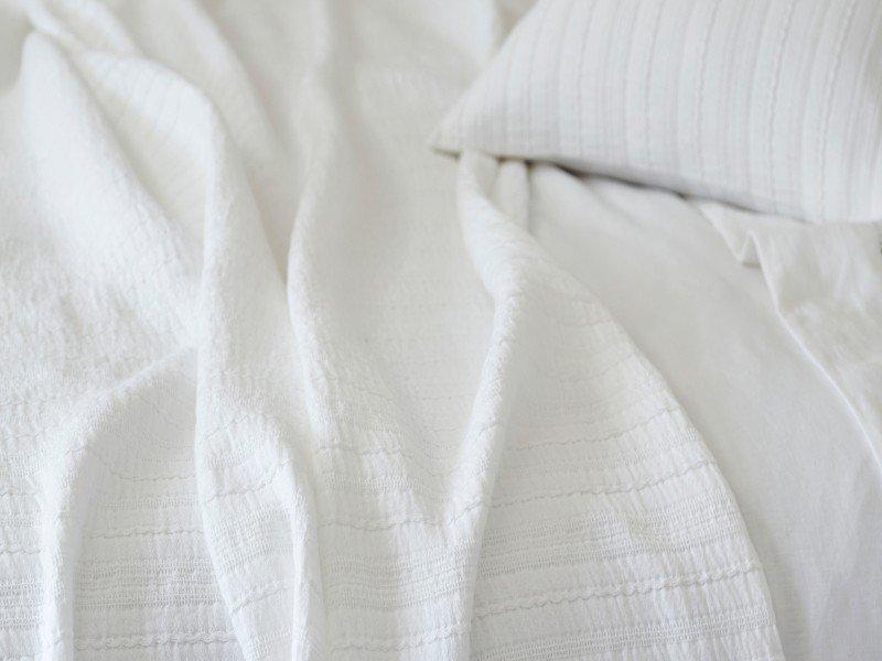 a woman sleeping in a bed with white sheets and pillows