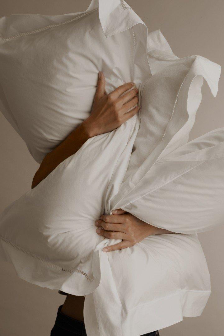 a woman is holding a pillow over her head and shoulders