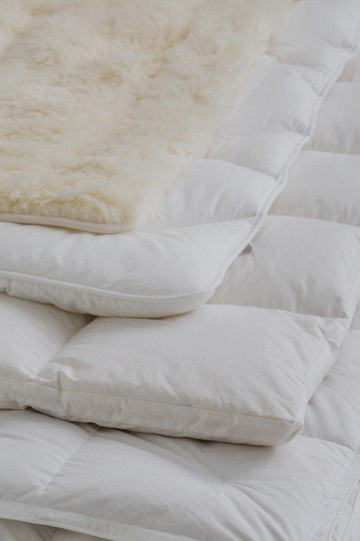 a bed with a white comforter and pillows on top of it