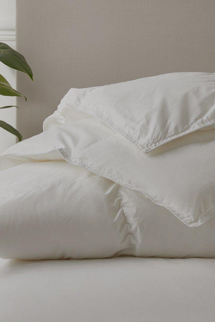 a bed with a white comforter and pillows on top of it