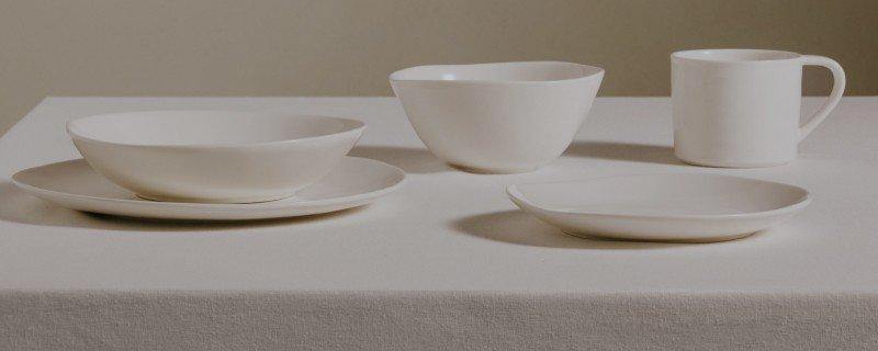 a white table with white dishes and cups on it