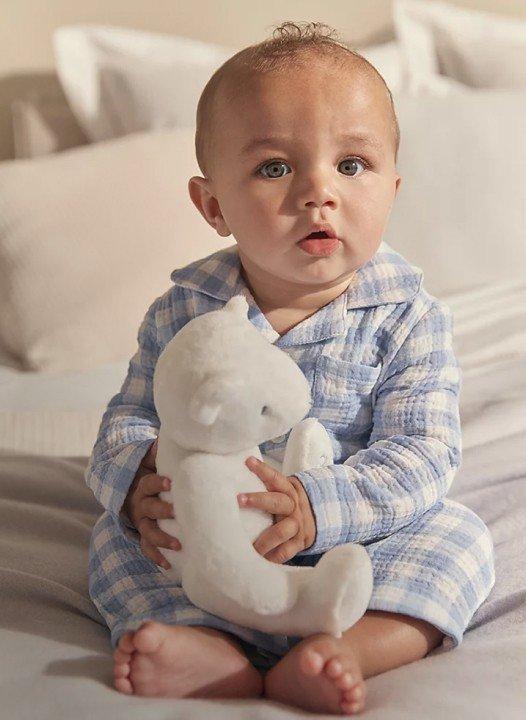 a baby sitting on a bed with a white blanket