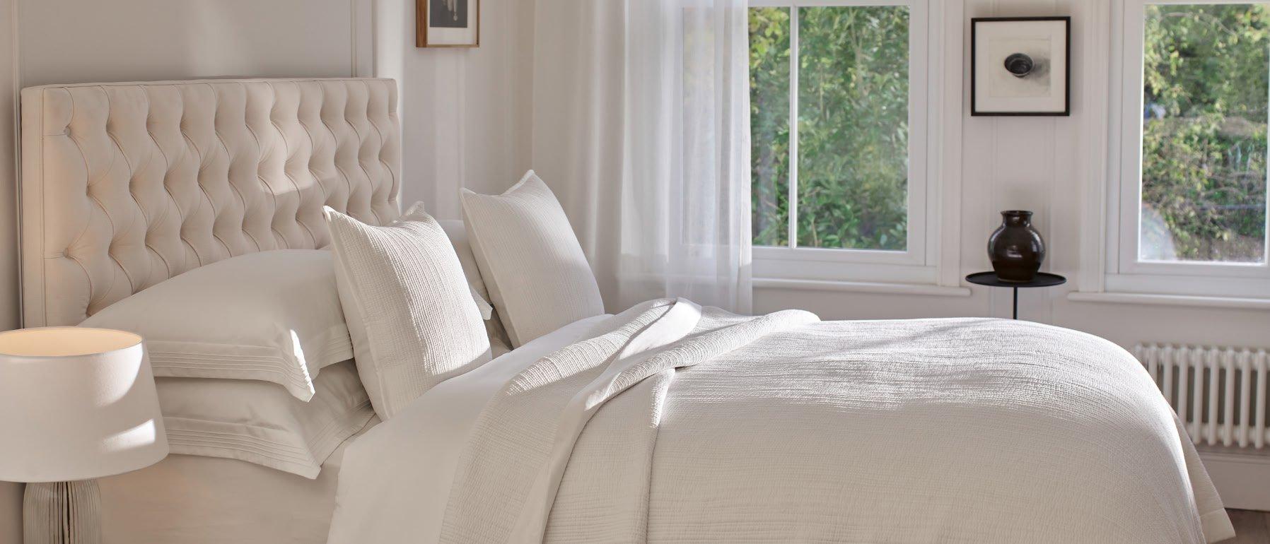 a white bed with a white comforter and pillows in a bedroom
