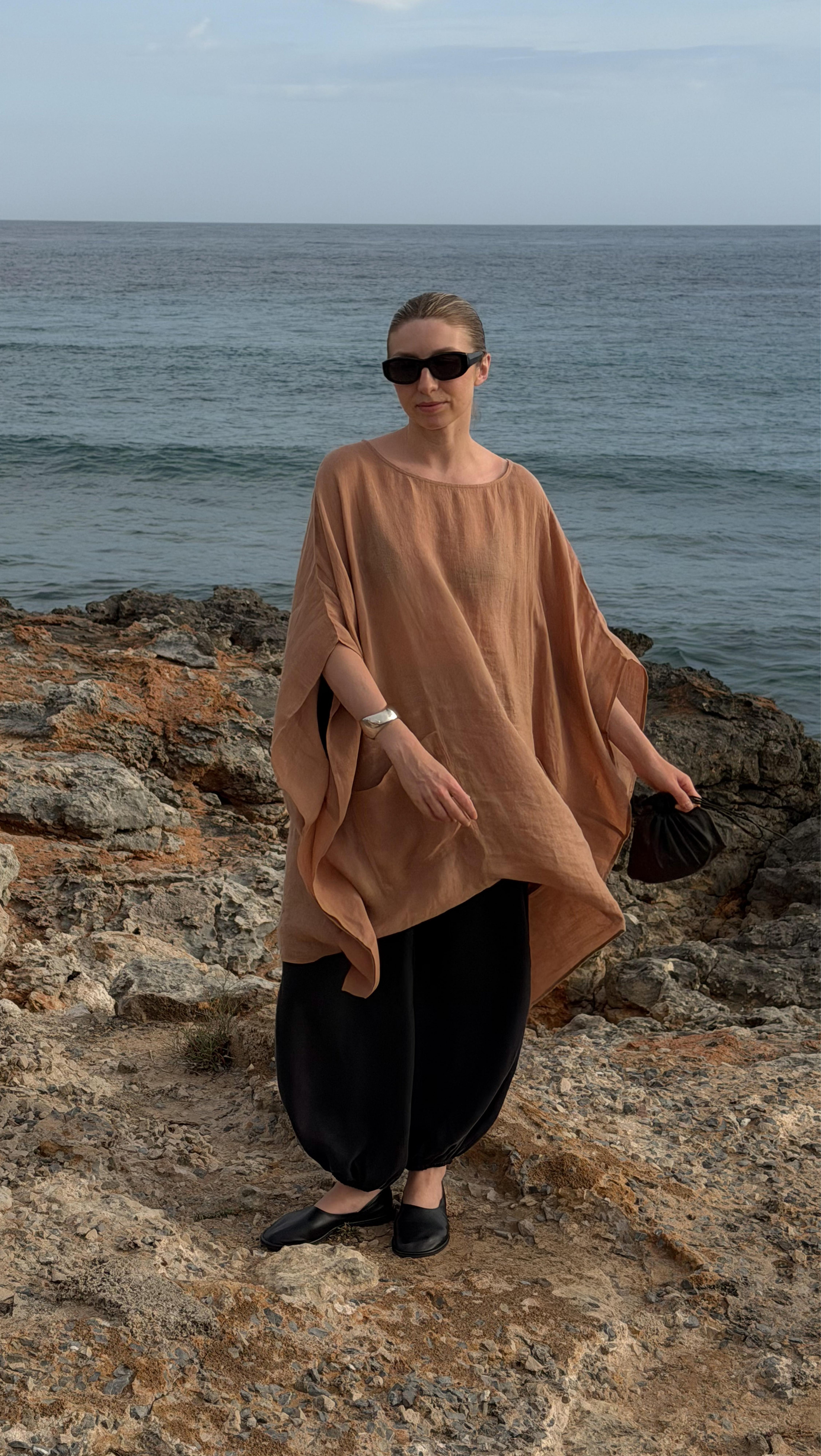 a woman standing on a rocky beach near the ocean