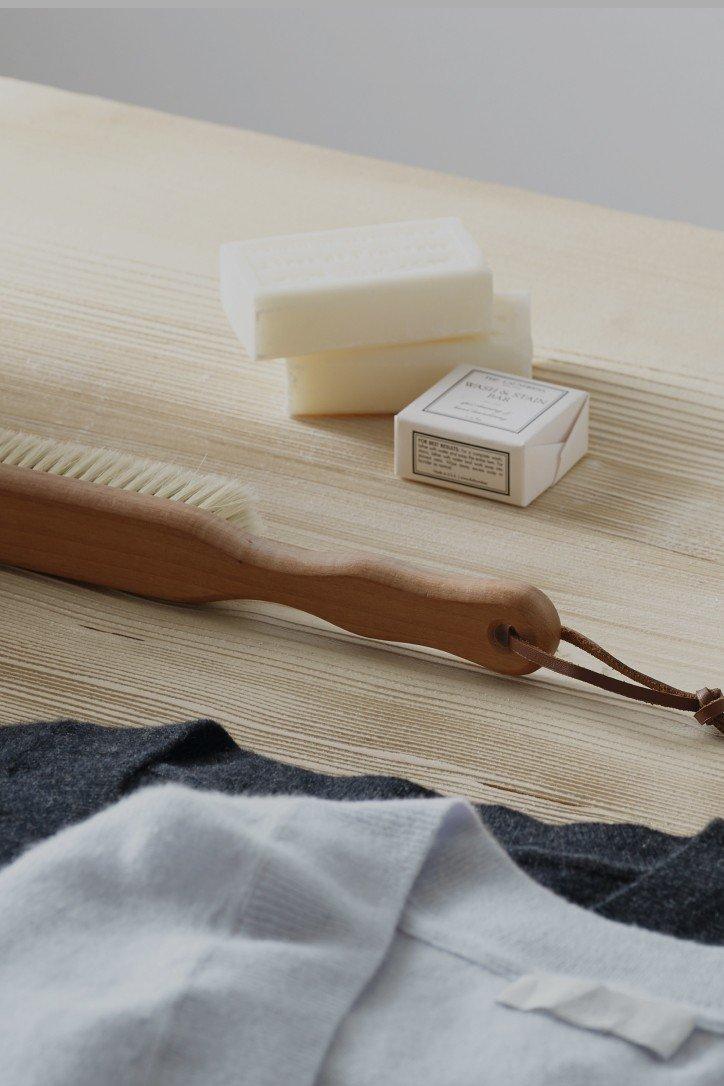 a wooden table with a brush, soap and a shirt on it