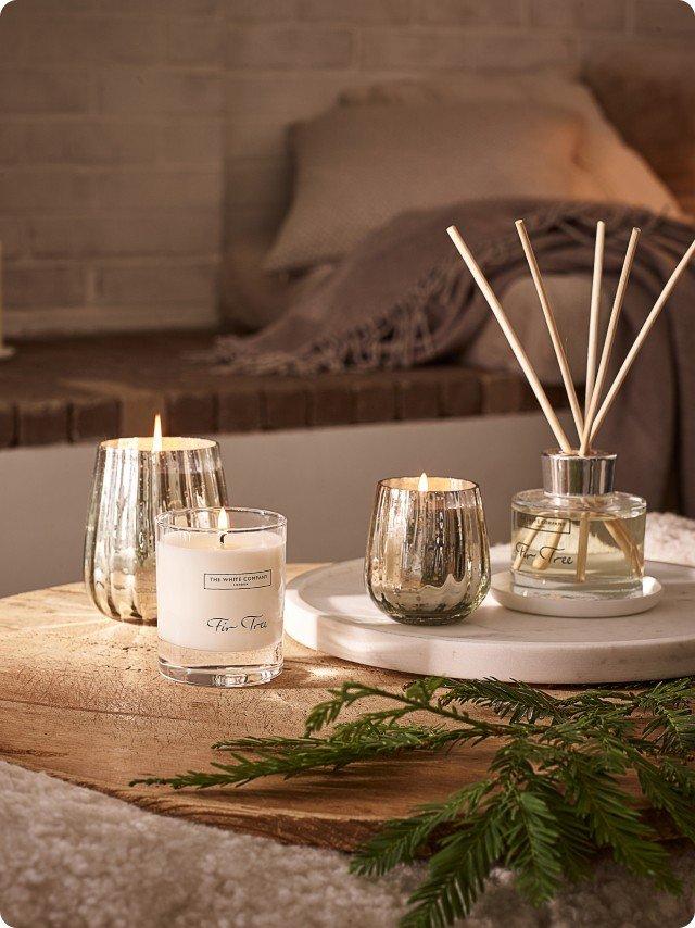 a table with candles, a diffuser and a plant on it