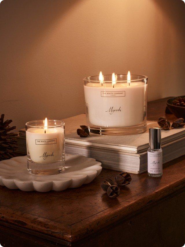 a candle and a bottle of perfume sit on a table