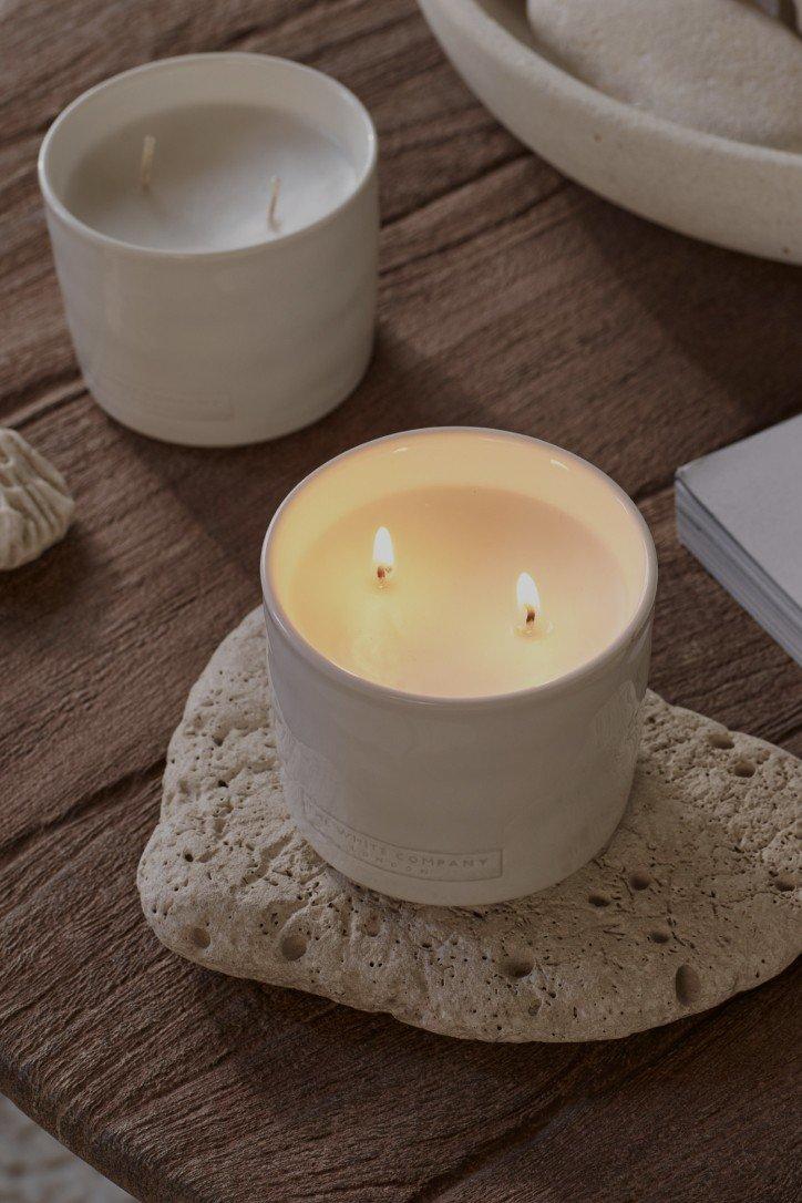 two candles on a table with a plant on top of it