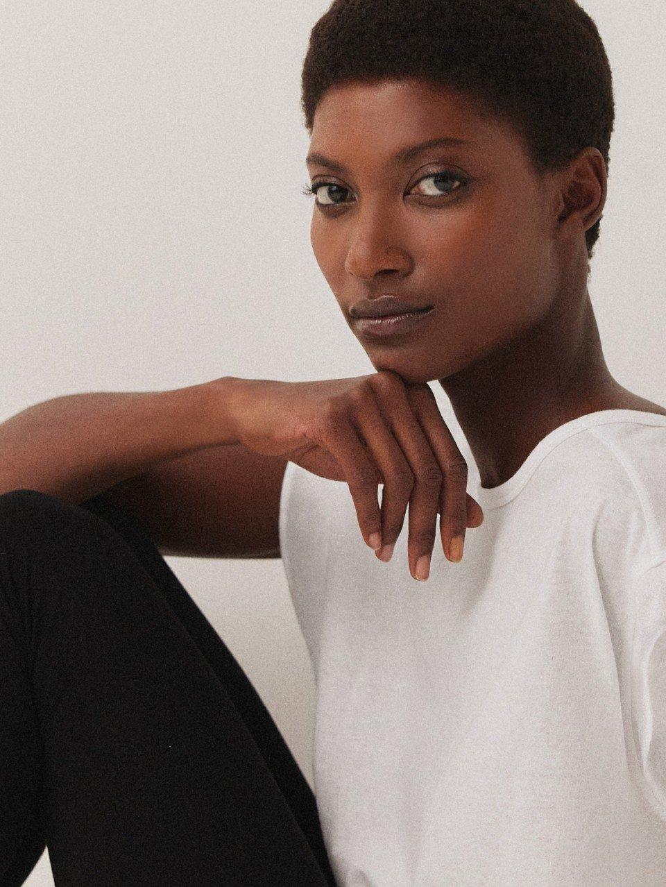 a woman in white shirt and black pants sitting on a chair