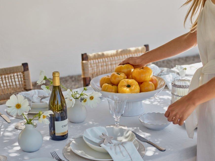 a woman is setting up a table with a bowl of fruit