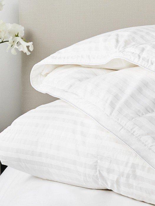 a stack of white pillows on top of a bed