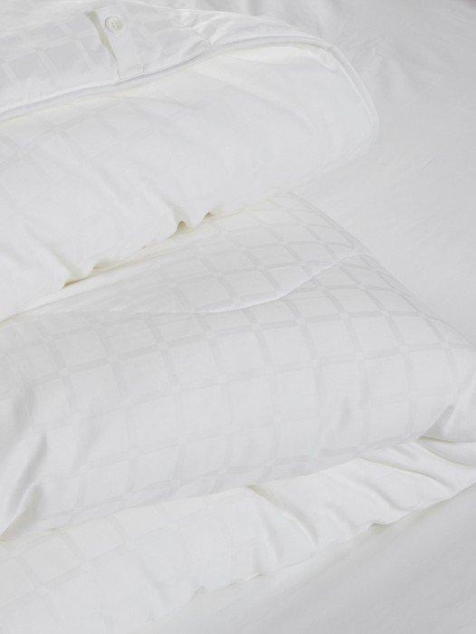 a stack of white pillows on top of a bed