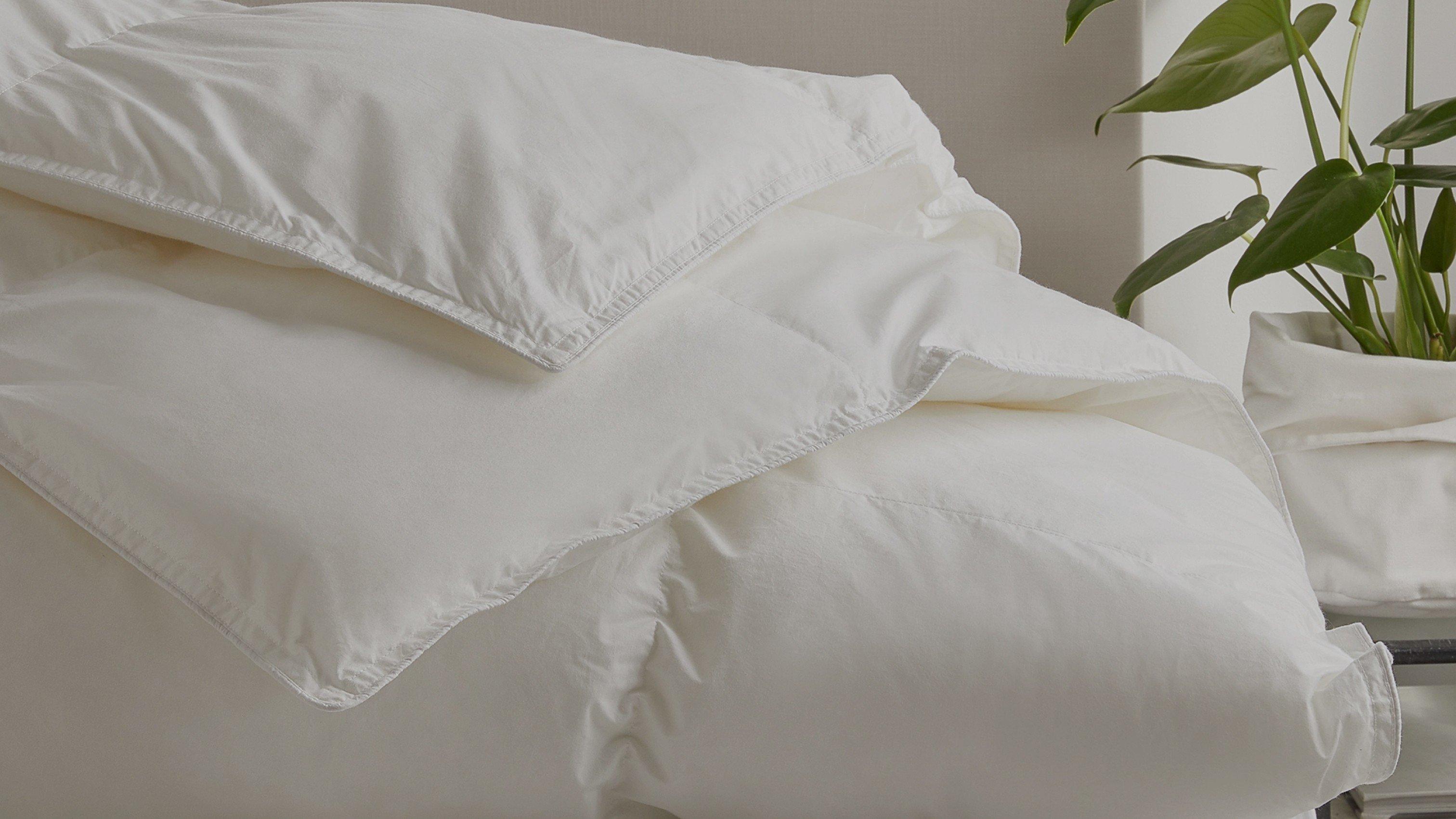 a bed with a white comforter and pillows on top of a white bed