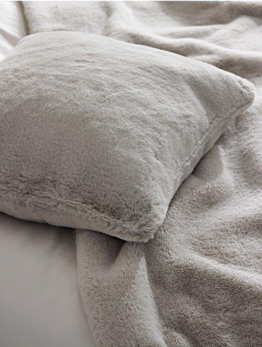 a close up of a pillow on a bed with a blanket