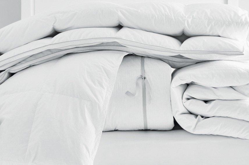 a bed with a pile of white pillows and blankets on top of it