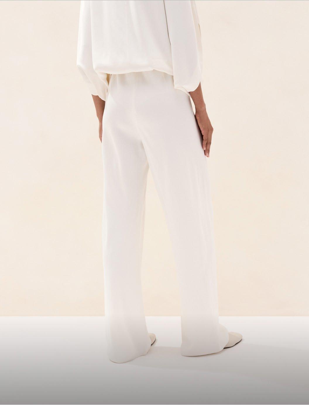 a woman in white pants and a white shirt standing